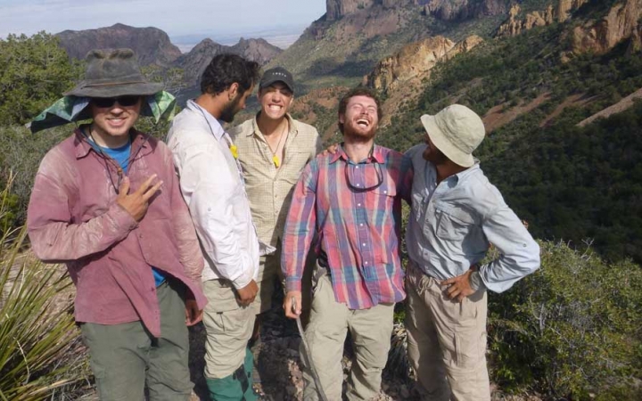 a group of people laugh in front of a mountainous desert landscape